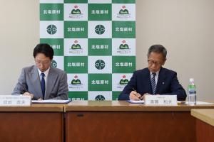 協定書に署名する遠藤村長と成田会津地方支部長