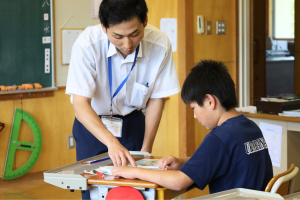 税金について教える役場職員と熱心に聞く生徒
